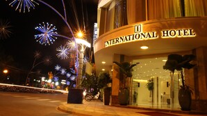 An International Hotel with a prominent entrance, large potted plants, and a well-lit facade. - International Hotel (Can Tho)