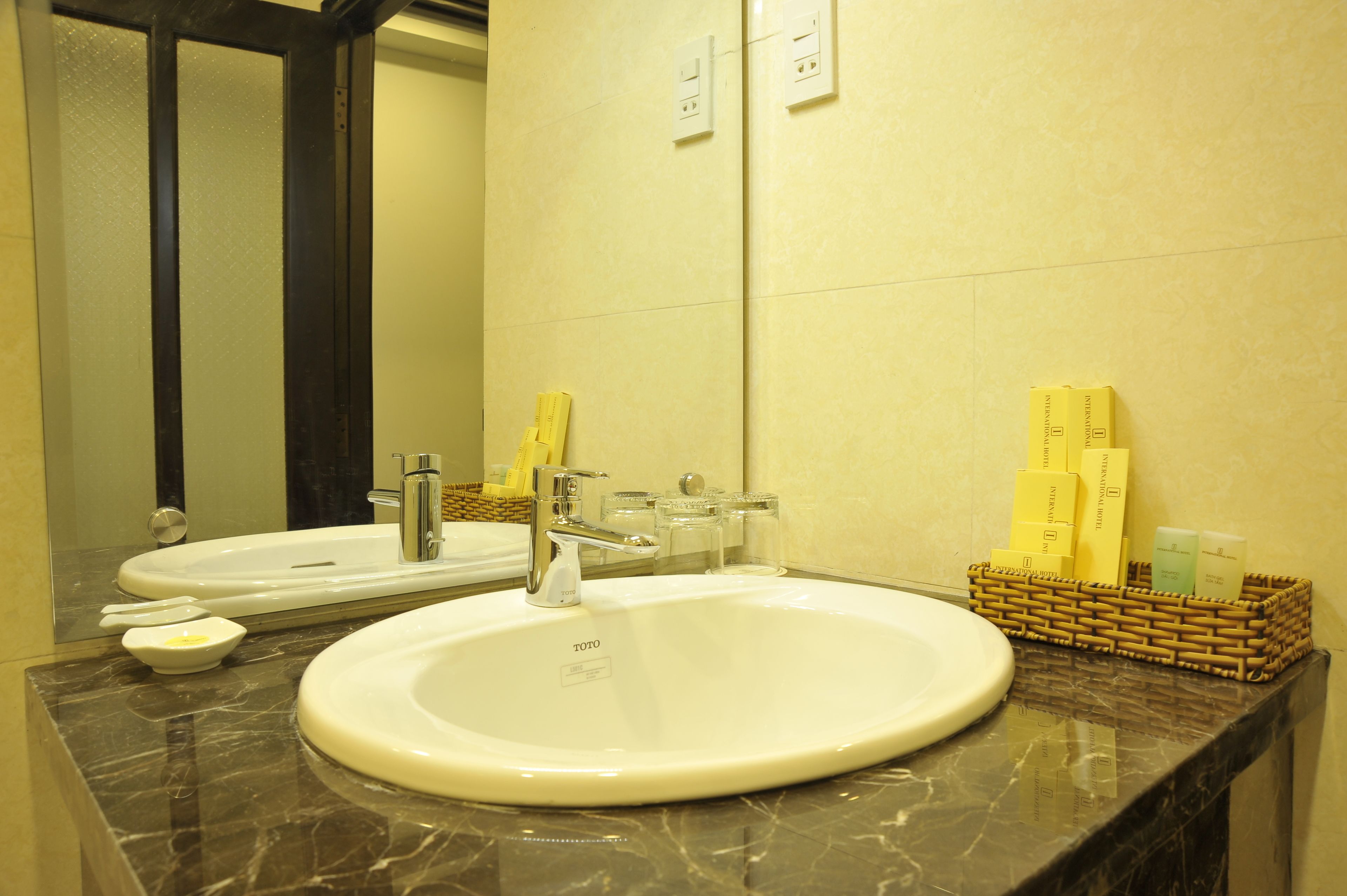A bathroom with two sinks, a mirror, and toiletries in a basket.