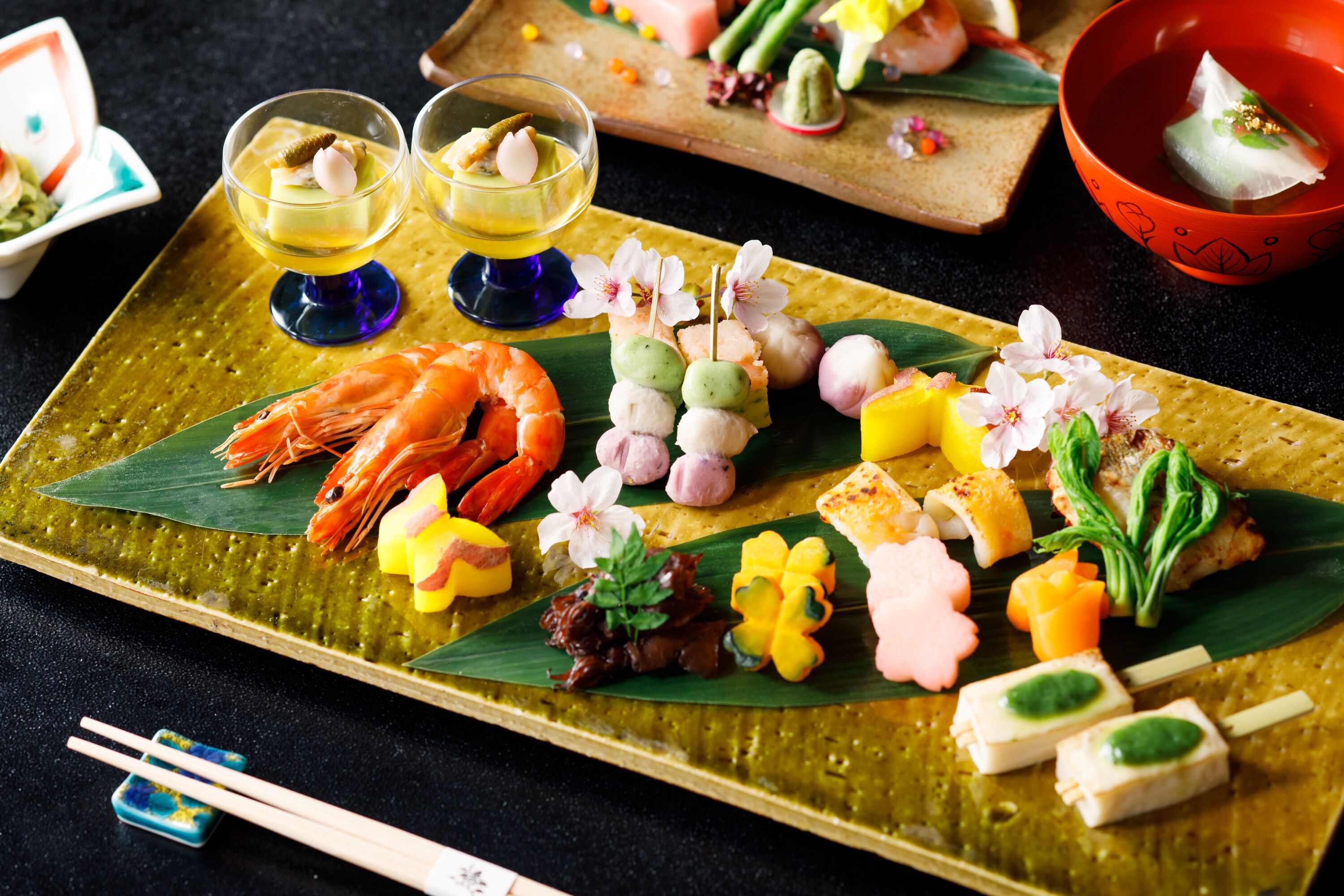 A variety of Japanese dishes arranged on a green ceramic plate.