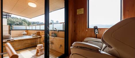 A wooden cabin with a sauna, a hot tub, and a massage chair.