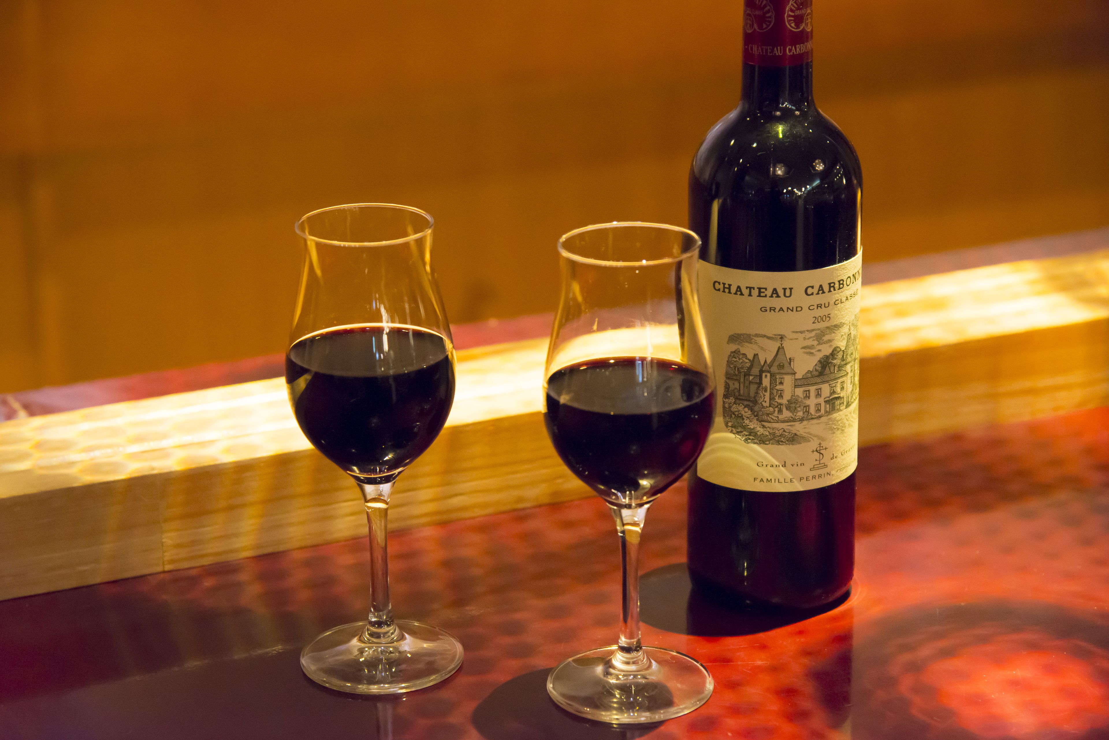 Two wine glasses and a bottle of Chateau Carbonat Grand Cru Classé 2005 on a table.