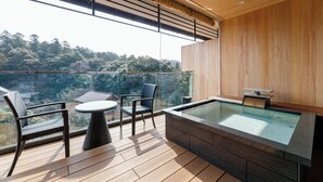 Un balcón moderno con jacuzzi de cubierta de vidrio, suelo de madera y dos sillas de mimbre.