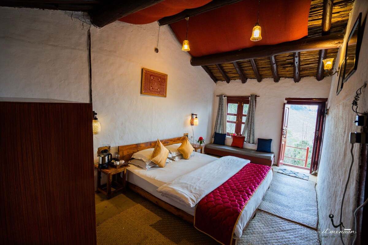 Ein gemütliches Schlafzimmer mit einem großen Bett, einem Holz-Kopfteil, einem Fenster mit Vorhängen und Blick ins Freie.
