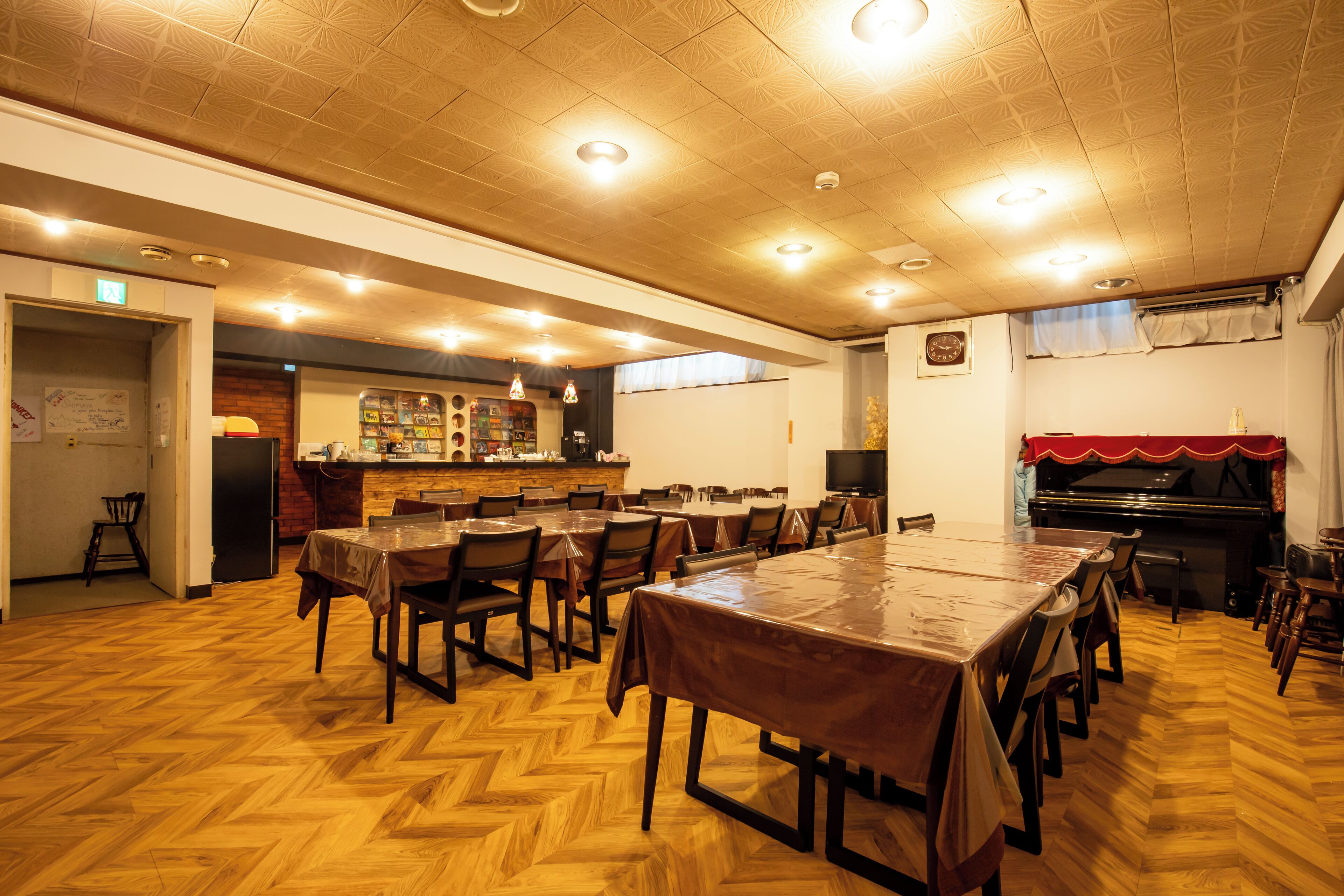 A spacious room with a long wooden table and chairs, a piano, and a bar area.