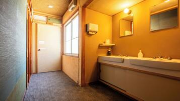 A hotel bathroom with a sink, mirror, and towel dispenser.