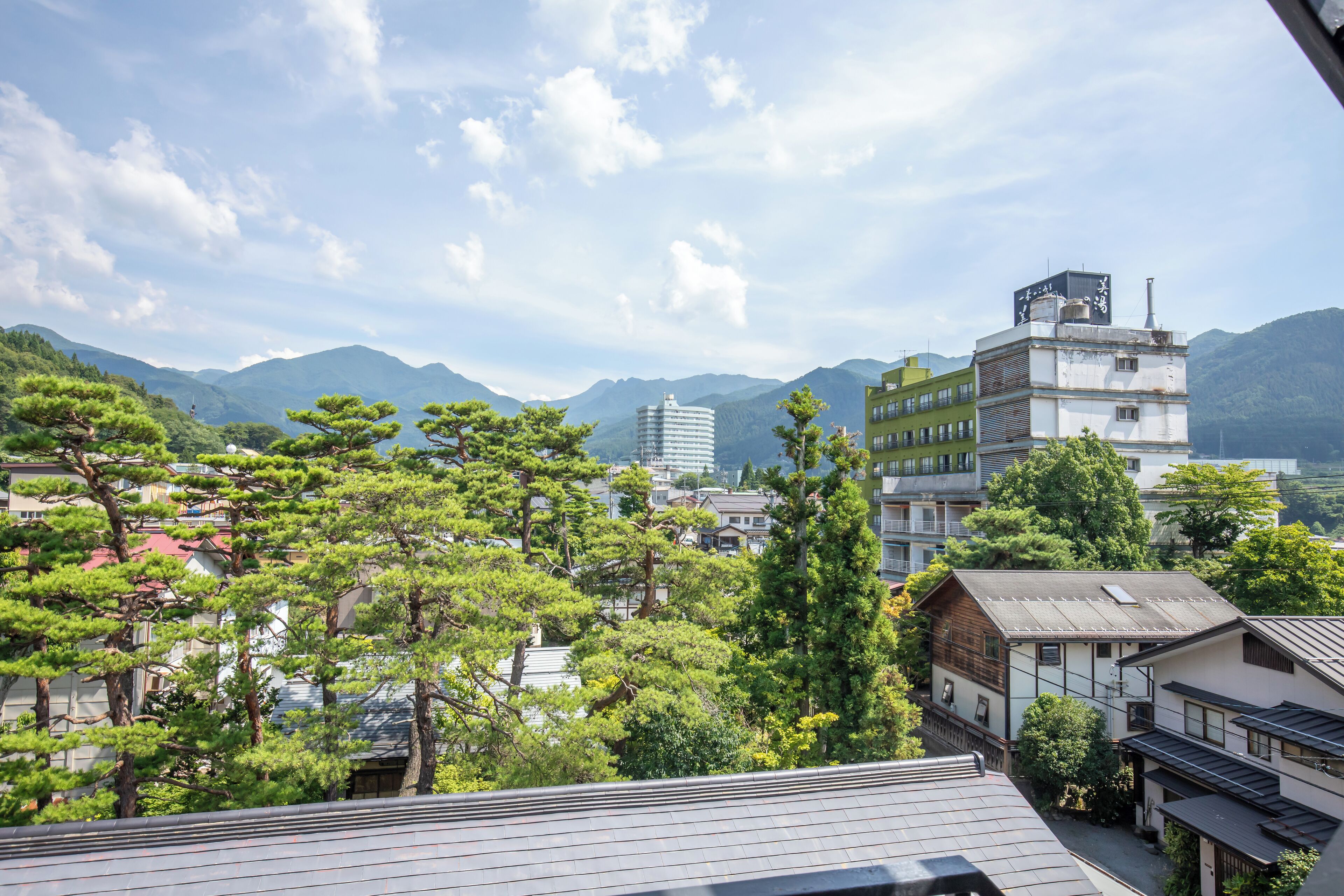 A traditional Japanese town with wooden buildings, surrounded by mountains and greenery.