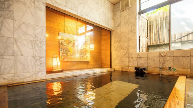 A spa area with a large wooden sliding door, a small wooden bench, and a tiled floor. - Shimaya (Yamanouchi)