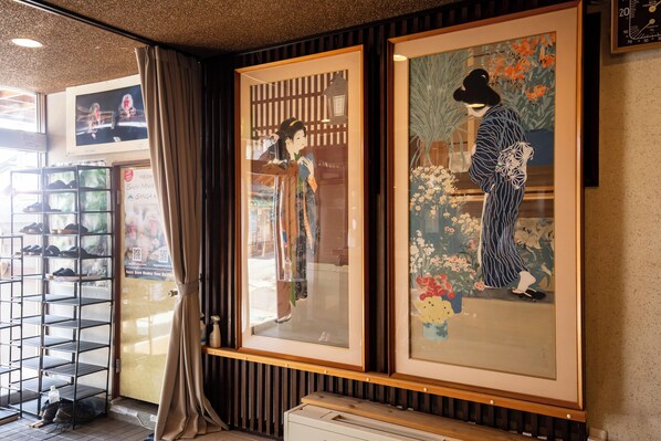 A room with traditional Japanese artwork, a shoe display, and a wooden floor.