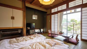 A traditional Japanese-style room with tatami flooring, a futon bed, a low table with cushions, and a sliding shoji screen door.