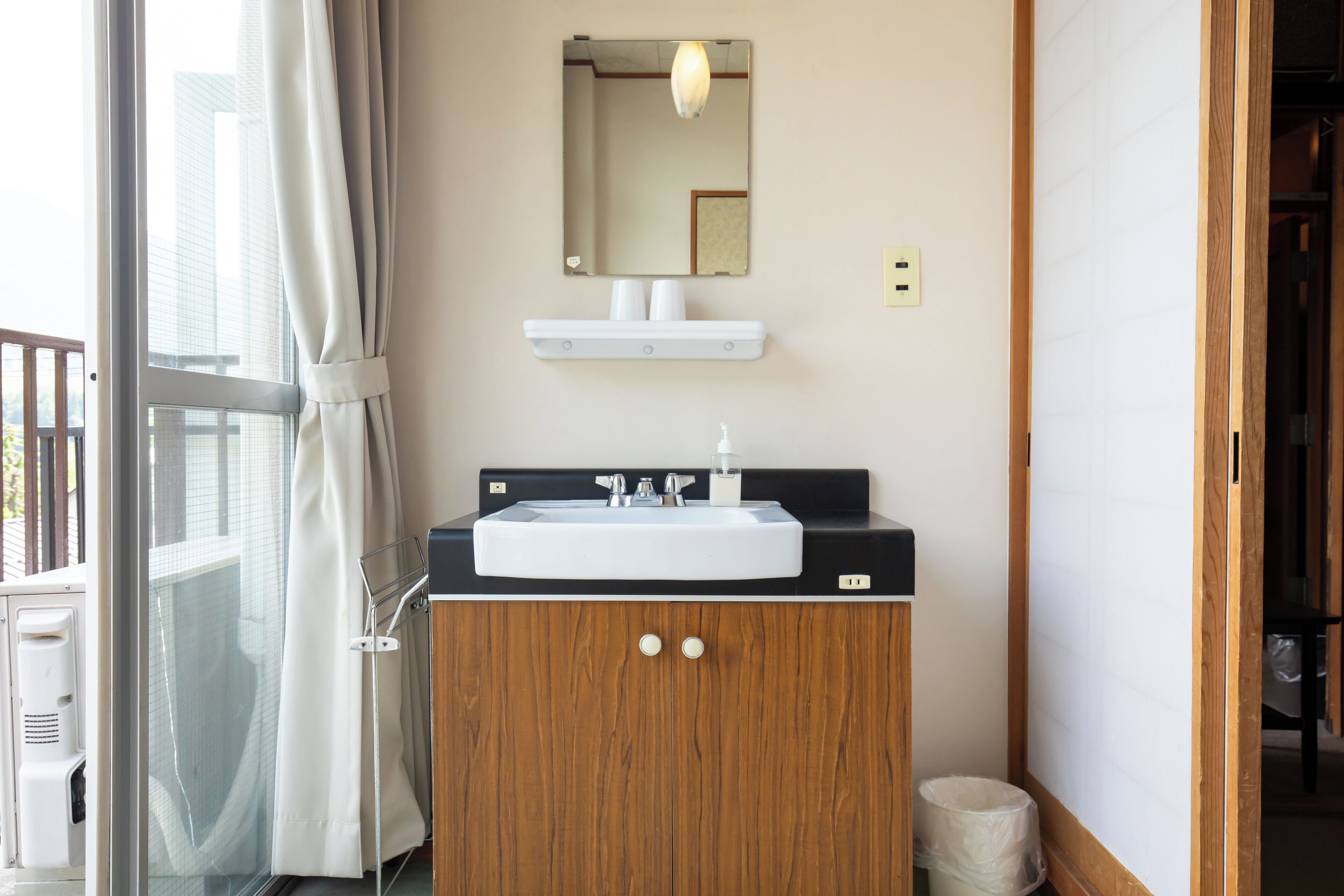 A bathroom with a sink, mirror, and wooden cabinet.