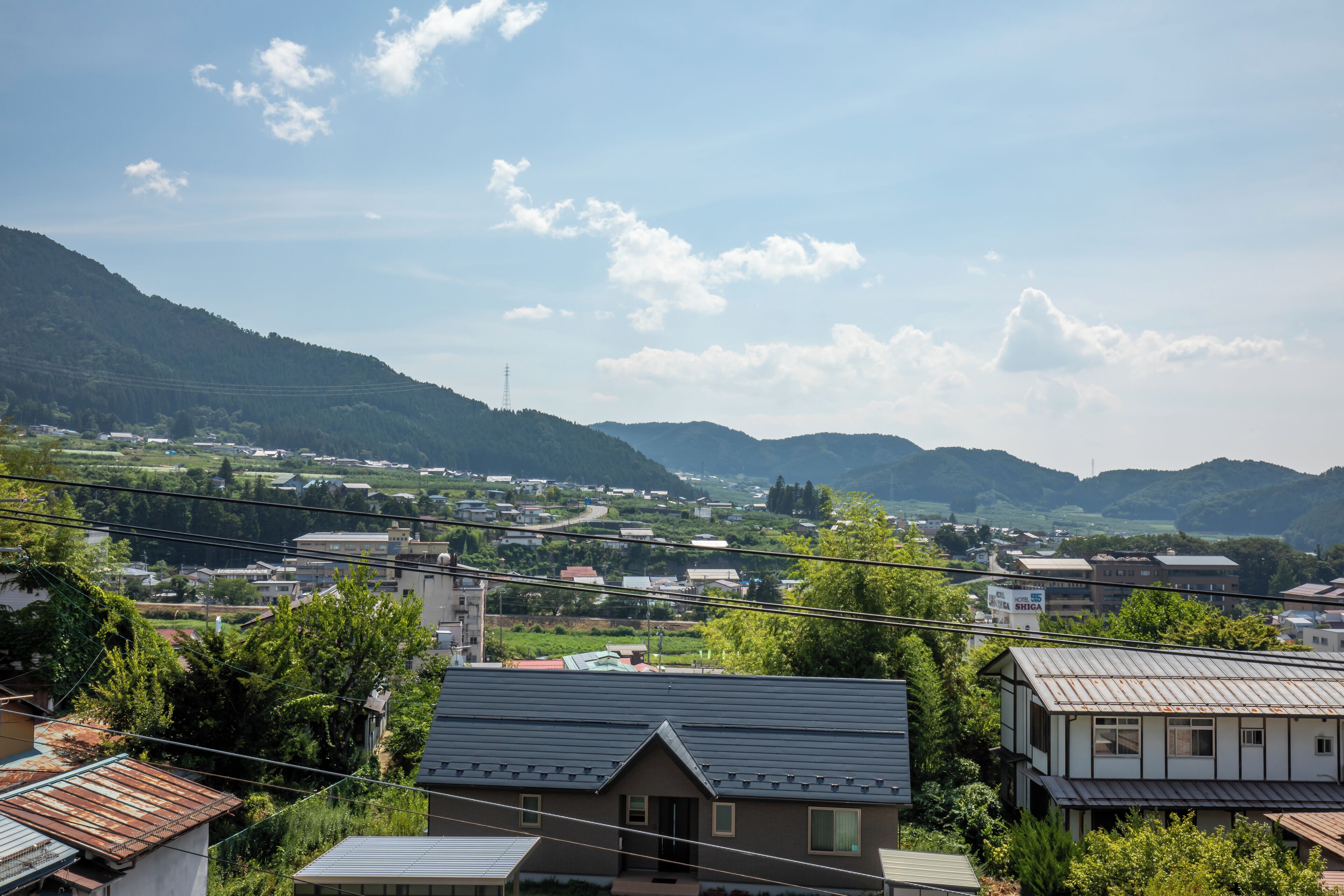 A residential area with houses, a clear sky, and distant hills.