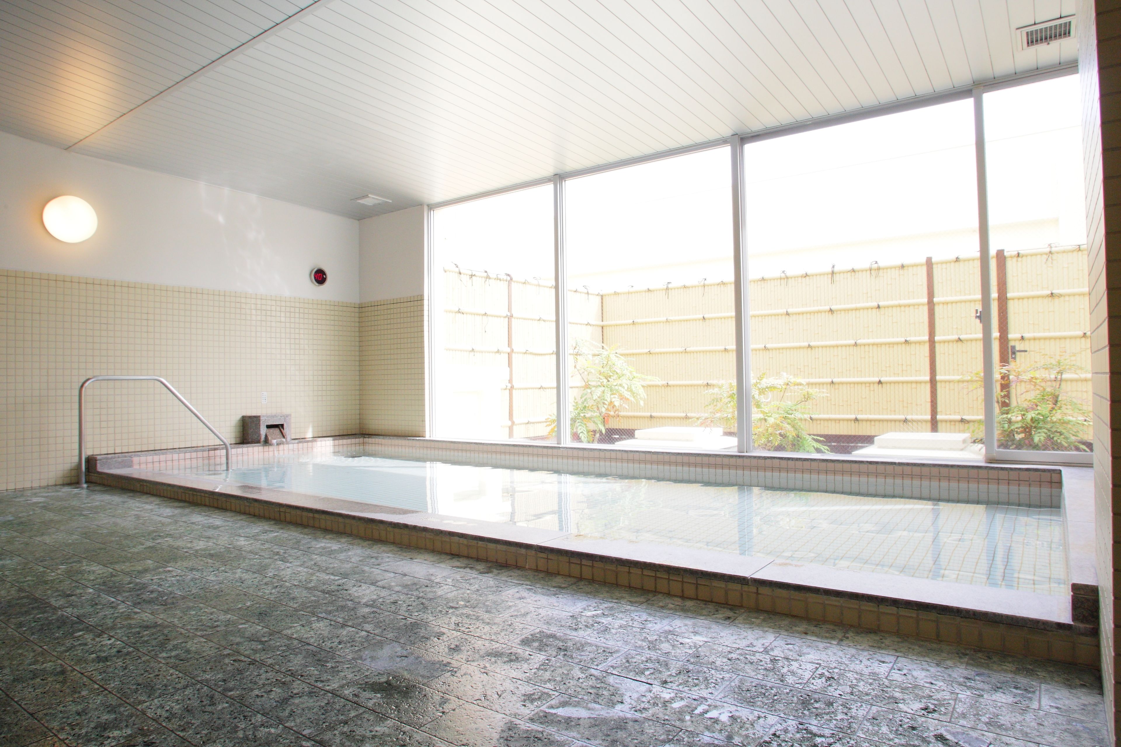 An indoor swimming pool with tiled walls and a large window.