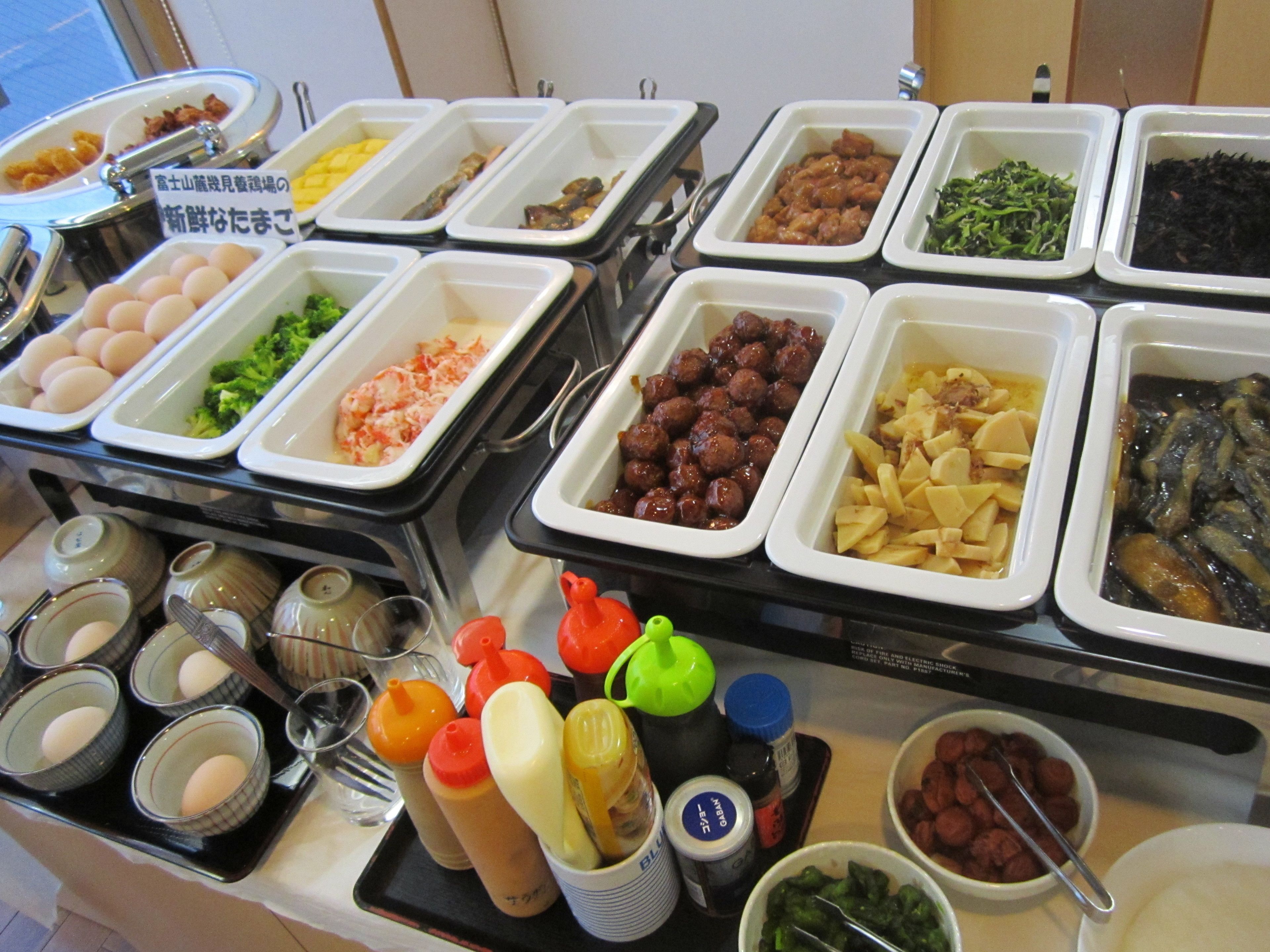 Un bufé con diversos alimentos, como huevos, brócoli, albóndigas y papas.