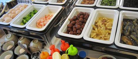 Un bufé con diversos alimentos, como huevos, brócoli, albóndigas y papas.