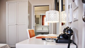 Une chambre d’hôtel avec une commode blanche, un miroir, une lampe et un téléphone.
