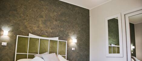 A bedroom with a large bed, a textured wall, and a mirror.