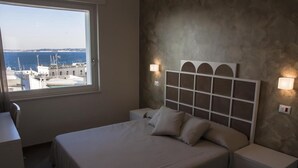 Une chambre à coucher avec un lit, des tables de chevet et une vue sur la mer.