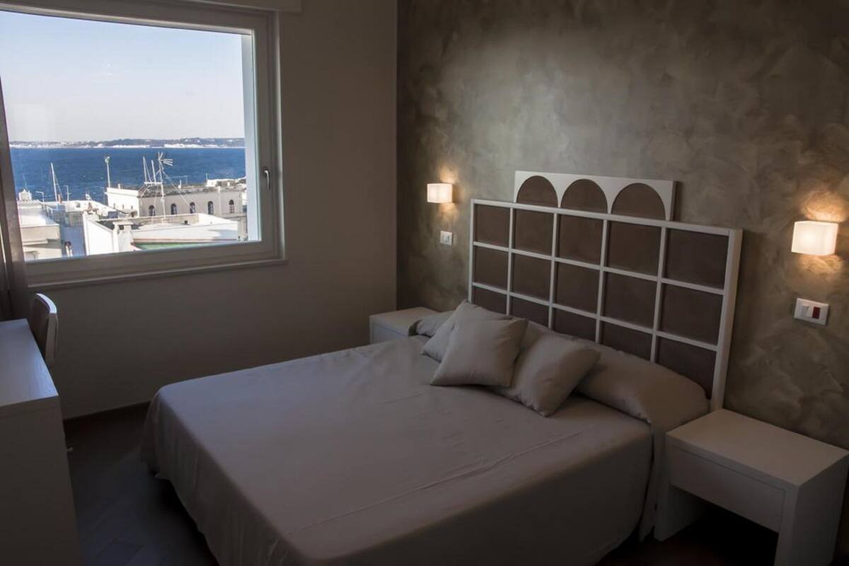 Una camera da letto con un letto, comodini e vista mare.