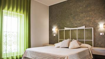 Un dormitorio con cama, cortinas verdes, pared texturizada y lámparas de noche.