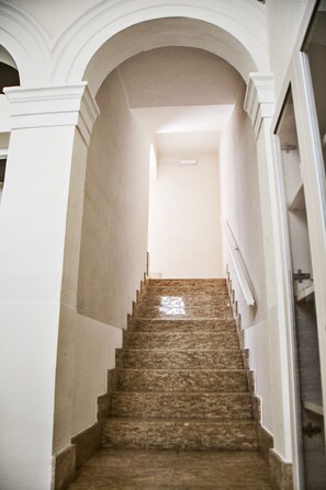 A marble staircase with a white wall on one side and a glass door on the other. - B&B Ghalà (Gallipoli)