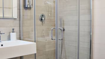 A modern bathroom with a glass-enclosed shower, a white sink, and a mirror above it.