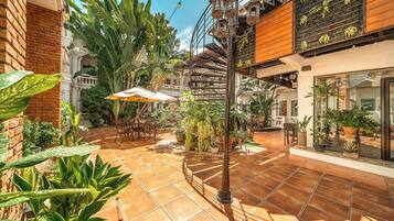 A courtyard with a tiled floor, outdoor seating, and various potted plants.
