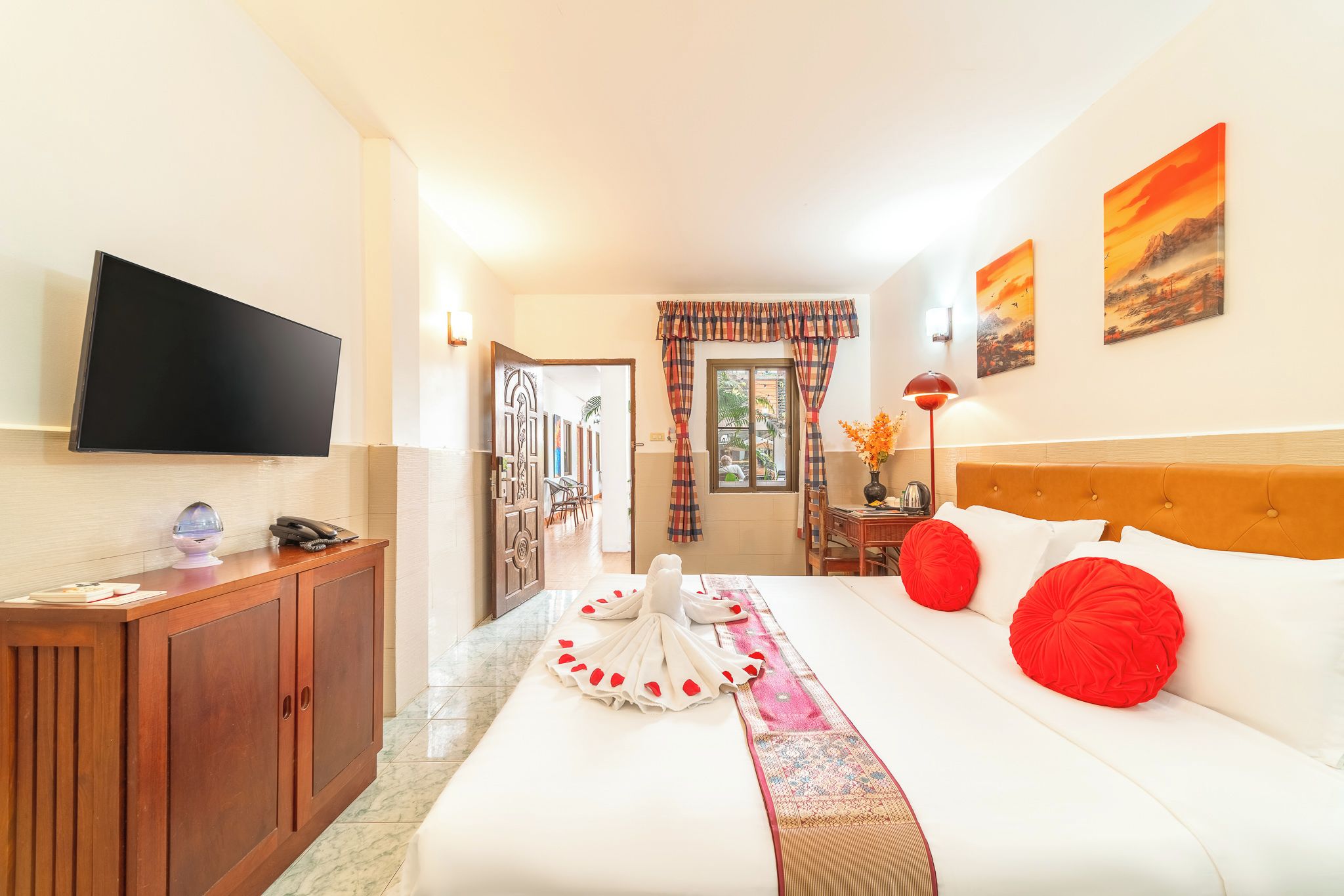 Une chambre d’hôtel équipée d’un lit, d’une télévision, d’un bureau avec un téléphone et offrant une vue sur l’extérieur.