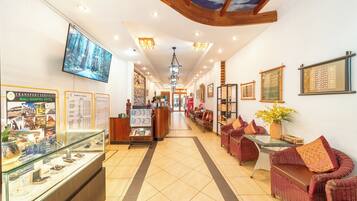 A hotel lobby with a reception desk, seating area, and a display case with informational brochures.