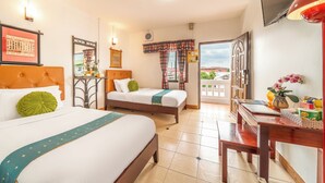 Habitación de hotel con dos camas, un escritorio, un televisor y un balcón con vistas.