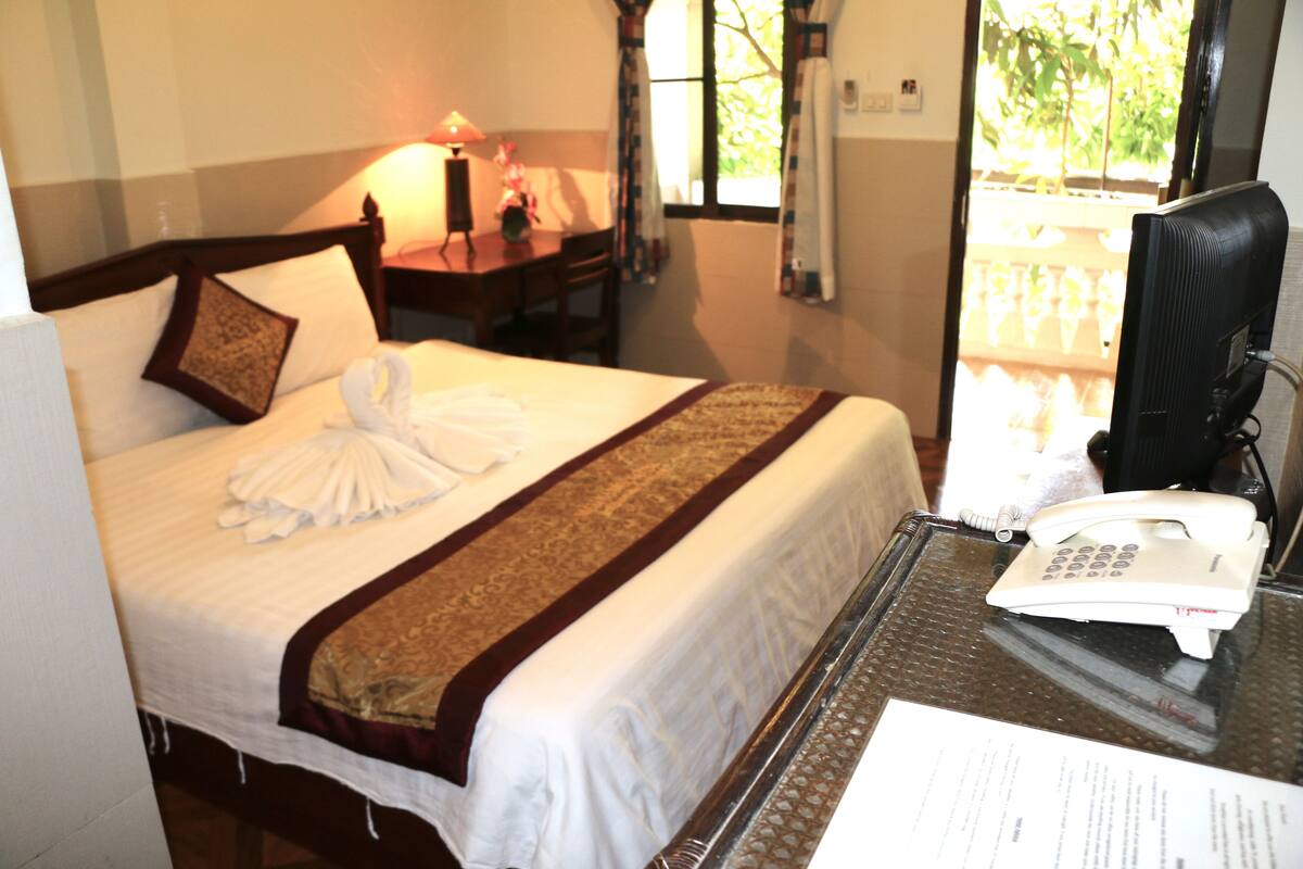 Una habitación de hotel con una cama bien hecha, un escritorio con lámpara y un teléfono.