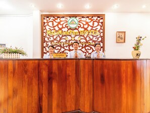 A reception desk with a wooden finish, a decorative wall with the hotel name, and a reception sign. - Mali Namphu Hotel (Vientiane)