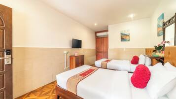 A hotel room with two beds, a television, a painting, and a wooden floor.
