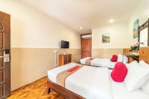Une chambre d’hôtel avec deux lits, une télévision, un tableau et un plancher en bois.