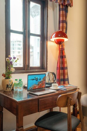 A wooden desk with a laptop, a cup, a kettle, and a vase with flowers. - Mali Namphu Hotel (Vientiane)