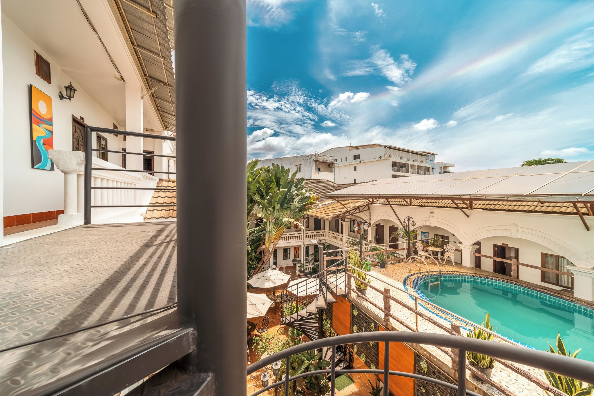 A hotel with a pool, outdoor seating, and a view of the surrounding buildings.