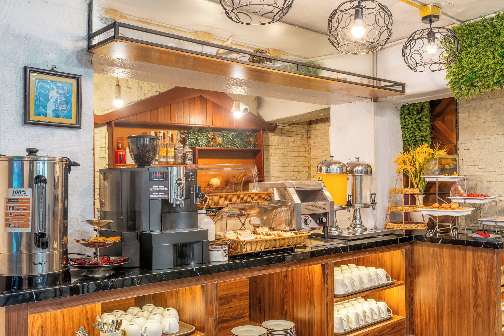 Una barra de desayuno tipo buffet con máquinas de café, panes variados y una selección de alimentos para el desayuno.