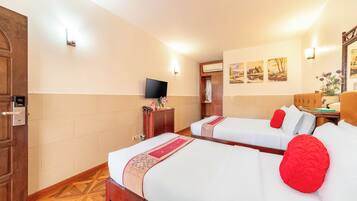A hotel room with two beds, a TV, and a wooden wardrobe.