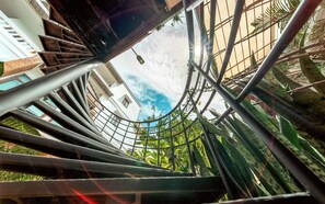 A spiral staircase with metal railings and a view of buildings and greenery in the background. - Mali Namphu Hotel (Vientiane)