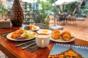 A table set with breakfast items including croissants, a cup of coffee, and a plate with various foods. - Mali Namphu Hotel (Vientiane)