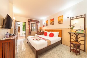 A hotel room with a bed, a desk, a chair, a television, and artwork on the walls. - Mali Namphu Hotel (Vientiane)
