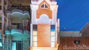 Un hotel de estilo arquitectónico tradicional, con una entrada destacada y un balcón con barandillas decorativas.