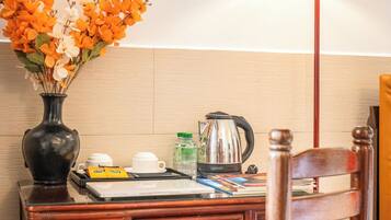 A wooden desk with a vase of flowers, a kettle, and a tray with cups and a teapot.