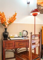 A wooden desk with a vase of flowers, a kettle, and a tray with cups and a teapot.