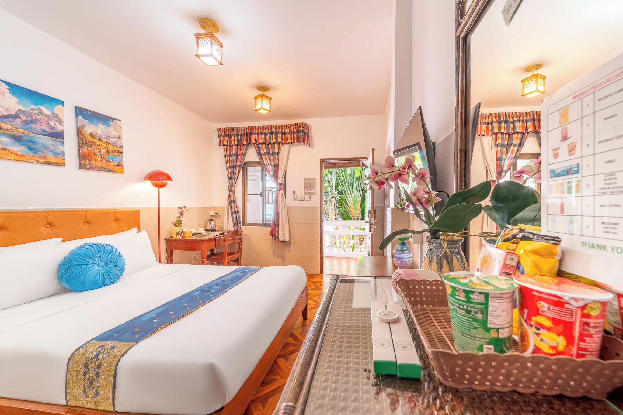 A hotel room with a bed, a desk, a chair, a window with curtains, a plant, and a breakfast tray.