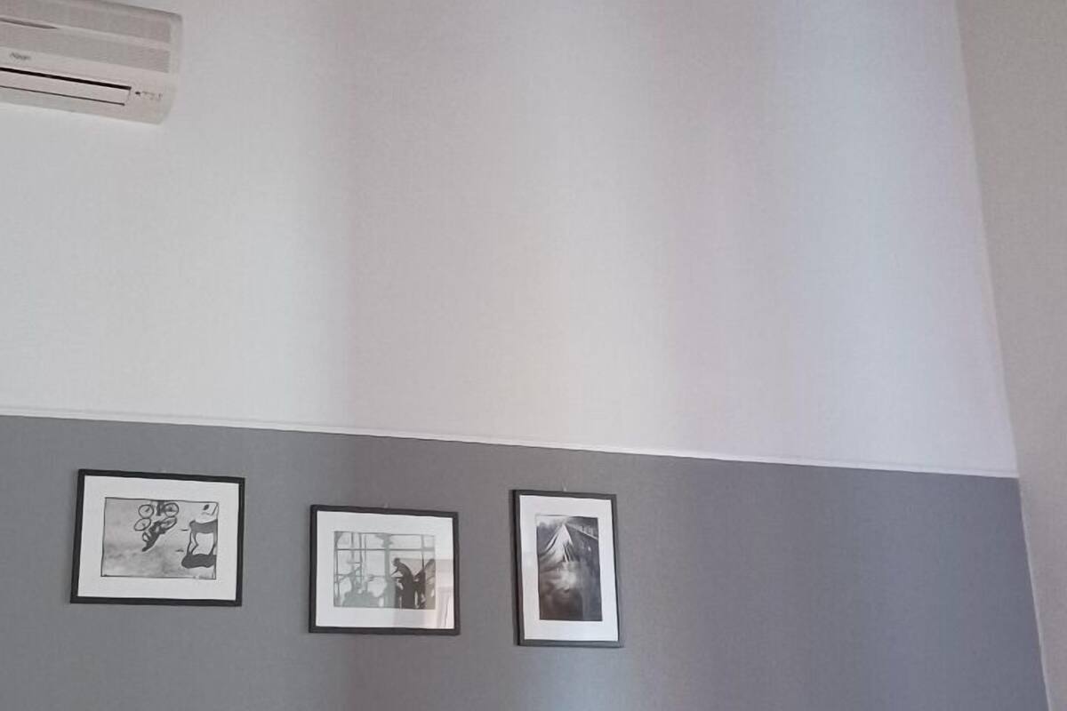 Habitación de hotel con cama, mesita de noche, lámpara y tres cuadros en la pared.