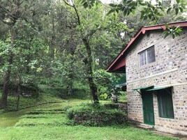 A stone building with a red roof, surrounded by lush greenery and trees.