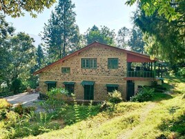 A stone building with a red roof, green shutters, and a porch.