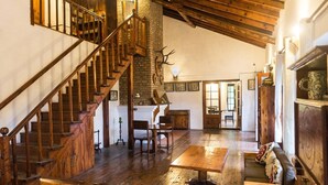 A spacious room with a wooden staircase, a fireplace, and a dining area. - Fredy's Bungalow (Nainital)