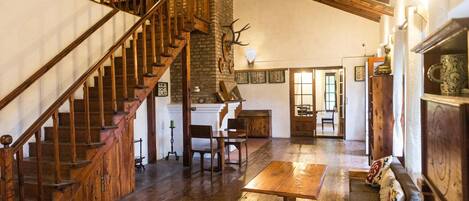 A spacious room with a wooden staircase, a fireplace, and a dining area.