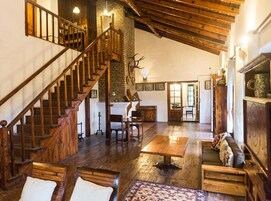 A spacious room with a wooden staircase, a fireplace, and a dining area.